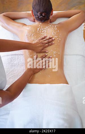 Auf dem Weg zu glatter, seidiger Haut. Rückansicht einer Frau, die eine Peelingbehandlung erhält. Stockfoto