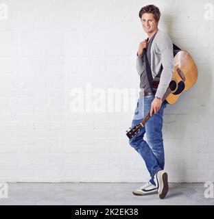 Sein musikalisches Talent zu teilen. Ein junger Mann mit Gitarre. Stockfoto