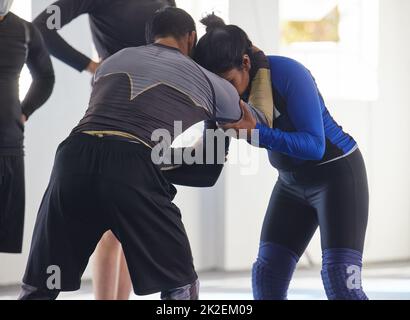 Zeigt ihr ein paar Bewegungen. Zugeschnittenes Bild eines Jiu-Jitsu-Sensei, der während eines Kurses mit einem seiner Schüler streitet. Stockfoto