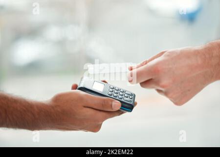 Tippen Sie auf, um zu bezahlen. Nahaufnahme eines nicht erkennbaren Mannes, der seine Rechnungen über einen drahtlosen Kartenleser bezahlt. Stockfoto