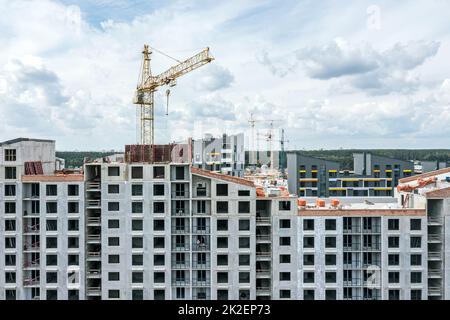 Luftaufnahme der städtischen Baustelle mit Wohngebäude und Kranen vor blauem bewölktem Himmel Hintergrund. Stockfoto