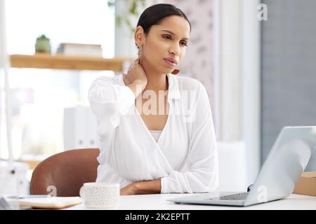 Brauchen Sie eine Pause. Aufnahme einer jungen Geschäftsfrau, die an einem Schreibtisch sitzt und in einem modernen Büro müde aussieht. Stockfoto