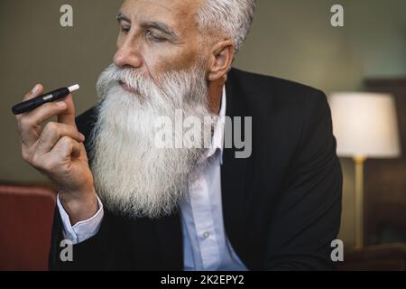 Schöner älterer Mann, der Tabak-Heizsystem raucht Stockfoto