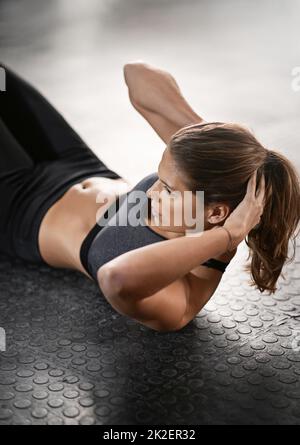 Es geht um deinen Kern. Aufnahme einer jungen Frau, die im Fitnessstudio Sit-ups macht. Stockfoto