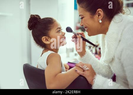 Ist das nicht genug, tusher schon, Mama. Aufnahme einer Mutter, die in einem Ankleidezimmer Make-up auf ihr süßes kleines Mädchen anwendet. Stockfoto