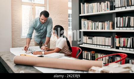 Technologie ist das Fundament ihres Fachwissens. Zugeschnittene Aufnahme von zwei aufstrebenden jungen Architekten, die ein digitales Tablet verwenden, während sie in einem modernen Büro zusammenarbeiten. Stockfoto