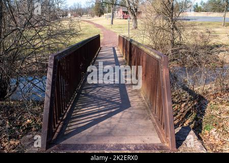 Eine Brücke überquert einen Bach und führt zu einem Wanderweg durch die Landschaft Stockfoto