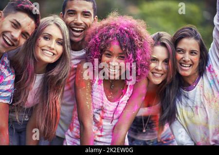 Erhellen Sie Ihren Tag. Glückliche Freunde, die Spaß mit Pulverfarbe haben. Stockfoto