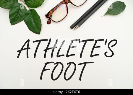 Text, der Inspiration für Athlete S IS Foot zeigt. Unternehmen zeigen eine Pilzinfektion des Fußes, gekennzeichnet durch Blasen Bürobedarf über Schreibtisch mit Tastatur und Gläsern und Kaffeetasse zum Arbeiten Stockfoto