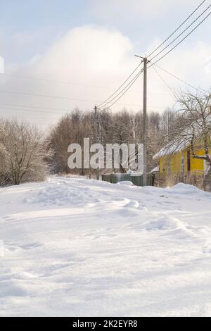 Schneebedeckte Dorfstraßen im Winter. Frostiger Morgen. Vertikales Bild Stockfoto