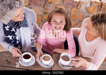 Lernen von Mutter zu Mutter. Drei Generationen der Frau der Frauen einer Familie, die draußen Tee trinken. Stockfoto