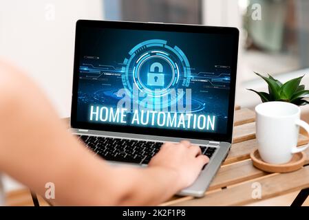 Schreiben mit Textanzeige Home Automation. Ein Wort zur Überwachung der elektrischen Aktivität des Hauses mit Technologie, Handtipps auf dem Laptop neben Coffe Becher und Plant Working From Home. Stockfoto