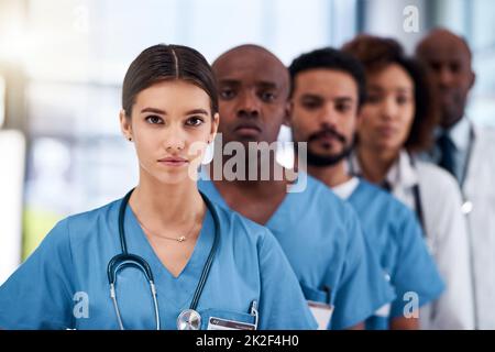 Sie stehen in der medizinischen Welt an erster Stelle. Porträt einer selbstbewussten jungen Gruppe von Ärzten, die tagsüber im Krankenhaus hinter einander stehen. Stockfoto