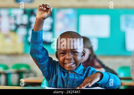 Ich habe einen Fragenlehrer. Ausgeschnittene Aufnahme eines Jungen aus der Grundschule, der im Klassenzimmer hochgezogen wurde. Stockfoto