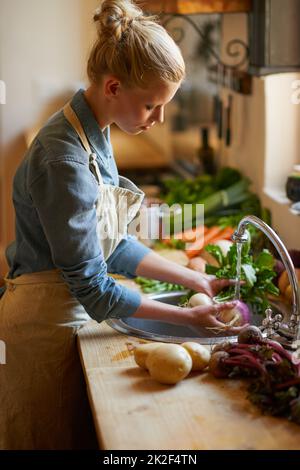 Essen ist eine Leidenschaft Aufnahme einer jungen Frau, die Gemüse in einer Spüle wäscht. Stockfoto