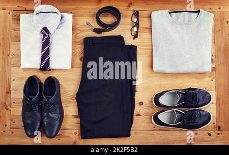 Elegant oder lässig. Ein schickes und legeres Outfit, das auf einem Holztisch ausgelegt ist, in einem hohen Winkel. Stockfoto