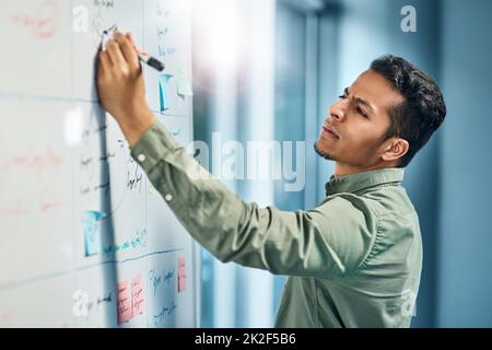 Sie können ihn immer hart bei der Arbeit finden. Aufnahme eines fokussierten jungen Geschäftsmannes, der tagsüber auf einem weißen Bild im Büro stand. Stockfoto