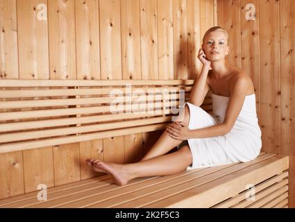 Das ist ihre Glückseligkeit. Eine wunderschöne blonde Frau, die sich in der Sauna entspannt. Stockfoto