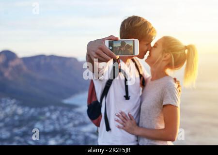 Den Kuss festhalten. Ausgeschnittene Aufnahme eines jungen Paares, das während einer Wanderung ein Selfie gemacht hat. Stockfoto