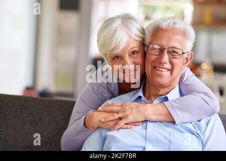 Am Ende... es lohnt sich alles. Porträt einer älteren Frau, die ihren Mann von hinten umarmt. Stockfoto