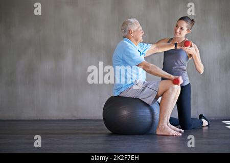 Patienten helfen, stark und gesund zu bleiben. Aufnahme eines Physiotherapeuten, der mit einem älteren Mann arbeitet. Stockfoto