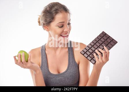 Shes ein Liebhaber von Schokolade. Studioaufnahme einer attraktiven jungen Frau, die von etwas Süßem verlockt wird. Stockfoto