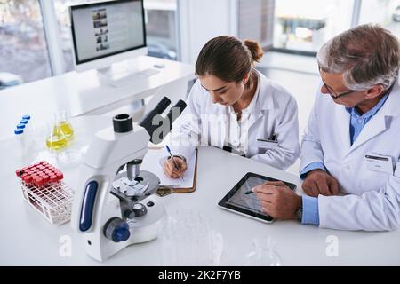 Eine vollständige, detaillierte Analyse der neuesten Ergebnisse. Aufnahme von zwei Wissenschaftlern, die in einem Labor diskutieren. Stockfoto