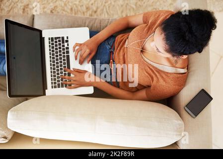 Ich hole meine sozialen Netzwerke auf. Aufnahme einer unkenntlichen Frau, die zu Hause einen Laptop benutzt. Stockfoto