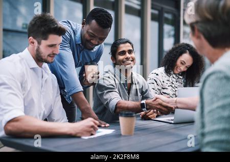 Gutes Geschäft basiert auf guten Beziehungen. Aufnahme eines Geschäftsmannes und einer Geschäftsfrau, die sich bei einem Treffen mit Kollegen die Hände schüttelten. Stockfoto