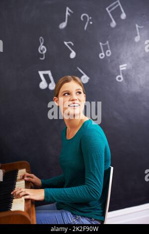 Musik machen. Aufnahme einer Frau, die vor dem Hintergrund von Musiknoten Klavier spielt. Stockfoto