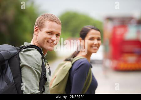 Man braucht keine Magie, um zu entäuschen, nur ein Ziel Ein Reisender lächelt an der Kamera, während er auf den Bus wartet. Stockfoto