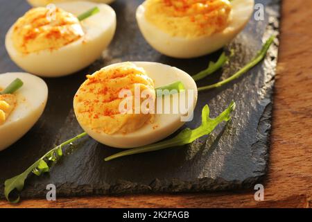 Deviled Eier mit rotem Pfeffer auf schwarzem Hintergrund Stockfoto