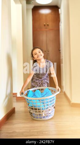 Shes eine große Hilfe rund um das Haus. Aufnahme eines jungen Mädchens, das einen Korb mit Wäsche in der Hand hält. Stockfoto