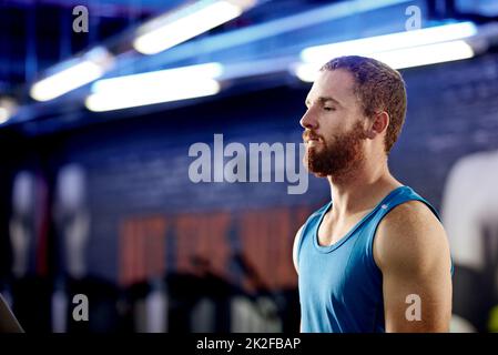 In den Trainingsbereich. Aufnahme eines jungen Mannes, der in einer Turnhalle steht. Stockfoto