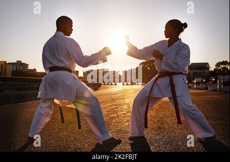 Bereit... kämpfen. Zwei Sportler stehen sich gegenüber und üben ihr Karate, während sie GI tragen. Stockfoto