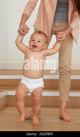 Kleine Schritte auf dem Weg zu großen Abenteuern. Eine kurze Aufnahme einer Mutter, die ihrem kleinen Jungen hilft, zu Hause zu gehen. Stockfoto