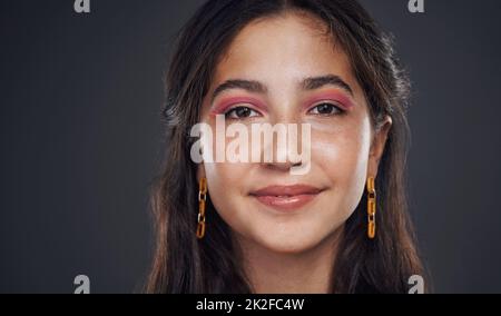 Ich bin zuversichtlich mit mir selbst. Beschnittenes Porträt eines attraktiven Teenagers, das allein vor dunklem Hintergrund im Studio steht. Stockfoto