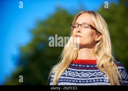 In der Wintersonne schwelgen. Aufnahme einer attraktiven jungen Frau, die einen Tag im Freien genießt. Stockfoto