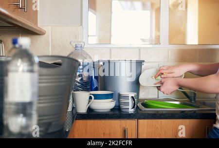 Eine weitere großartige Möglichkeit, Wasser zu sparen. Kurzer Schuss einer unkenntlichen Frau, die zu Hause Geschirr macht und versucht, Wasser in der Küche zu sparen. Stockfoto