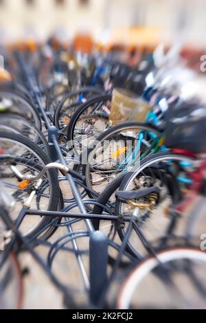 Ein verschwommenes Foto von vielen geparkten Fahrrädern. Symbolischer Inhalt. Stockfoto