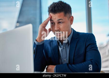 Das war nicht das, was ich erwartet hatte. Aufnahme eines hübschen jungen Geschäftsmannes, der allein im Büro sitzt und sich gestresst fühlt, während er seinen Laptop benutzt. Stockfoto