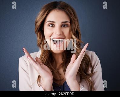 Ich habe einige Neuigkeiten über das Spiel erhalten. Studioportrait einer attraktiven jungen Geschäftsfrau, die vor dunkelblauem Hintergrund überrascht aussieht. Stockfoto