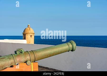 Alte Eisenkanone und Wachhaus an den Wänden der historischen Festung von Farol da Barra Stockfoto