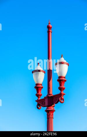 Alte rote Straßenlampe mit blauem Himmel im Hintergrund Stockfoto