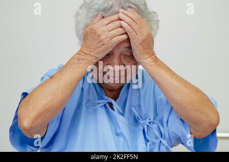 Asiatische ältere ältere Frau Patientin Kopfschmerzen im Bett im Krankenhaus, medizinisches Konzept. Stockfoto