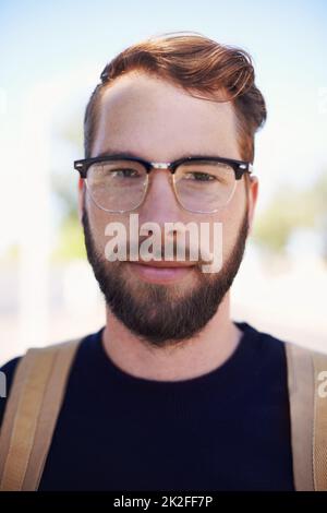 Der Inbegriff von Geek trifft auf Hip trifft auf den modernen Hipster. Ein hübscher junger Hipster im Freien, während er eine Brille trägt. Stockfoto