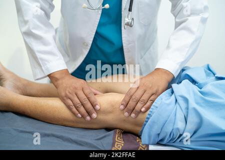 Asiatischer Arzt Physiotherapeut Untersuchung, Massage und Behandlung von Knie und Bein von älteren Patienten in der orthopädischen medizinischen Klinik Krankenschwester Krankenhaus. Stockfoto