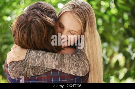 Jung und voller Leidenschaft. Porträt eines lächelnden jungen Paares, das sich im Park umarmt. Stockfoto