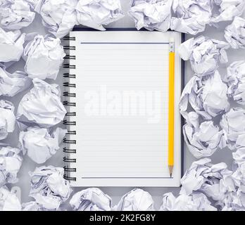 Weißes Notizblock auf weißem Hintergrund. Um die Notizblöcke liegt viel zerknittert Papier, Copy Space Stockfoto