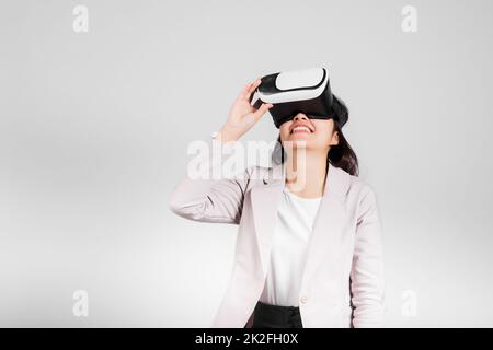 Lächelnde Frau, die begeistert ist Tragen Sie ein VR-Headset während des Virtual-Reality-Erlebnisses Stockfoto